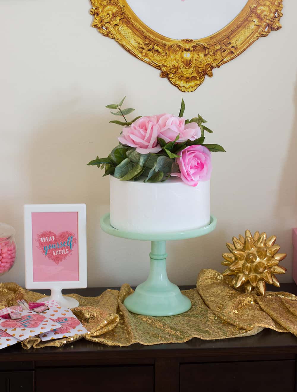 White cake topped with DIY faux flower cake topper on mint stand 