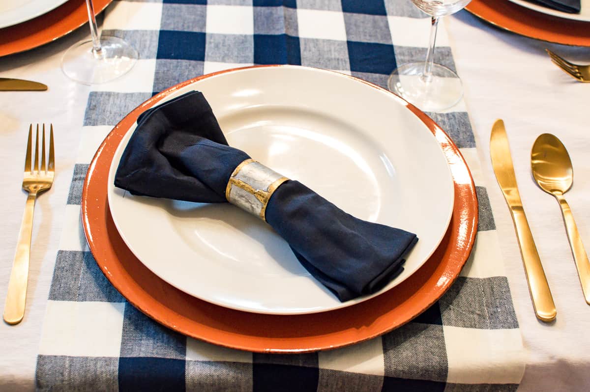 Thanksgiving place setting with orange charger and blue napkin