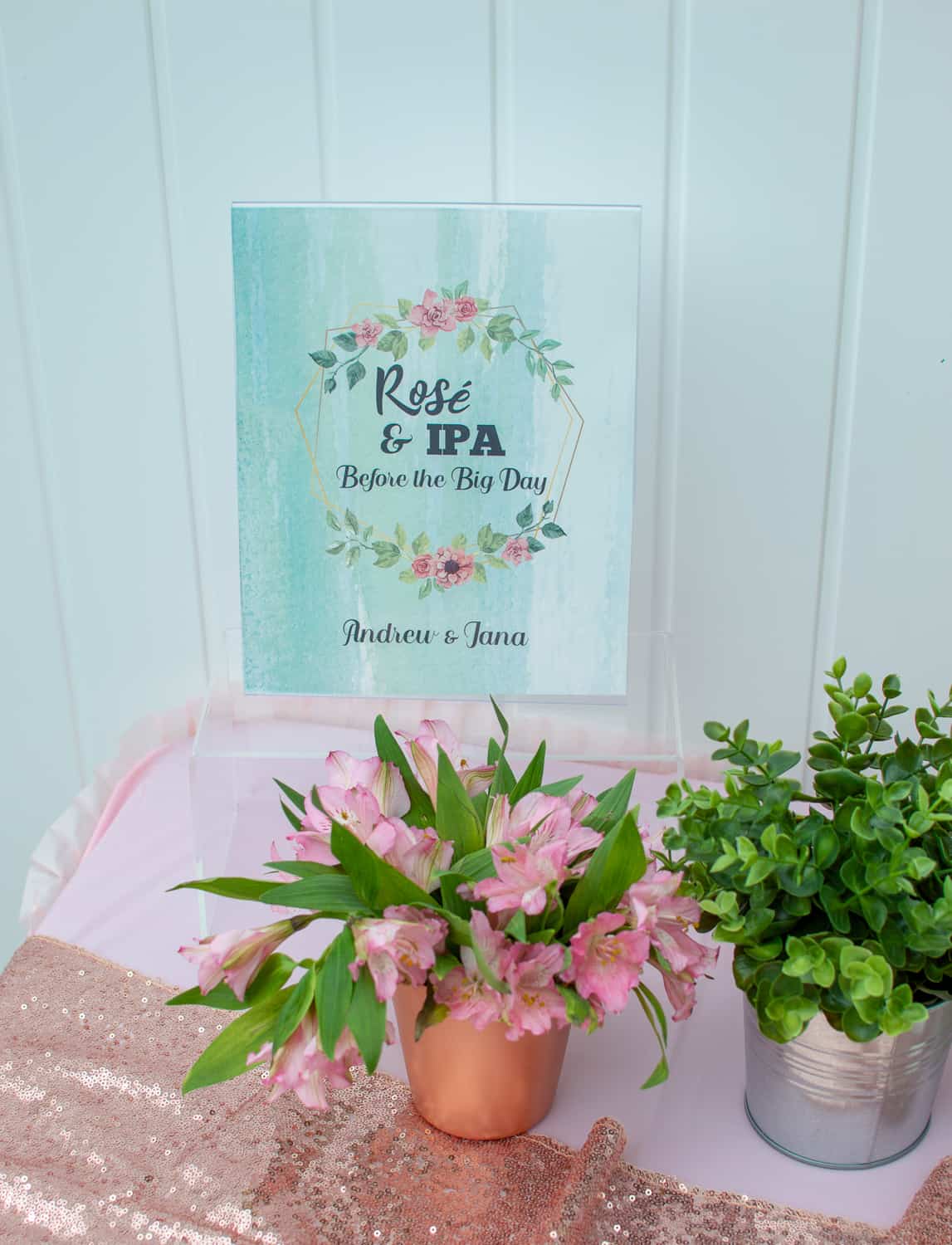 Rosé and IPA party sign along with flowers and greenery 